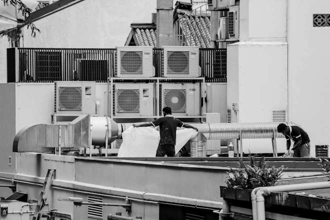 Two technicians work among rooftop air-conditioning units